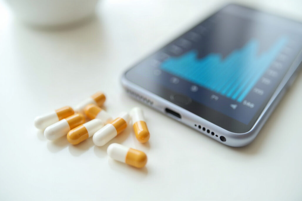 Supplement capsules beside a phone showing a glucose chart